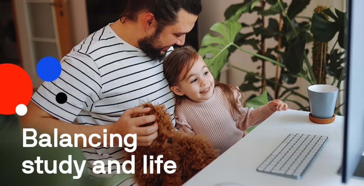 A man holding his daughter while working on a computer, illustrating the challenge of balancing study and life.
