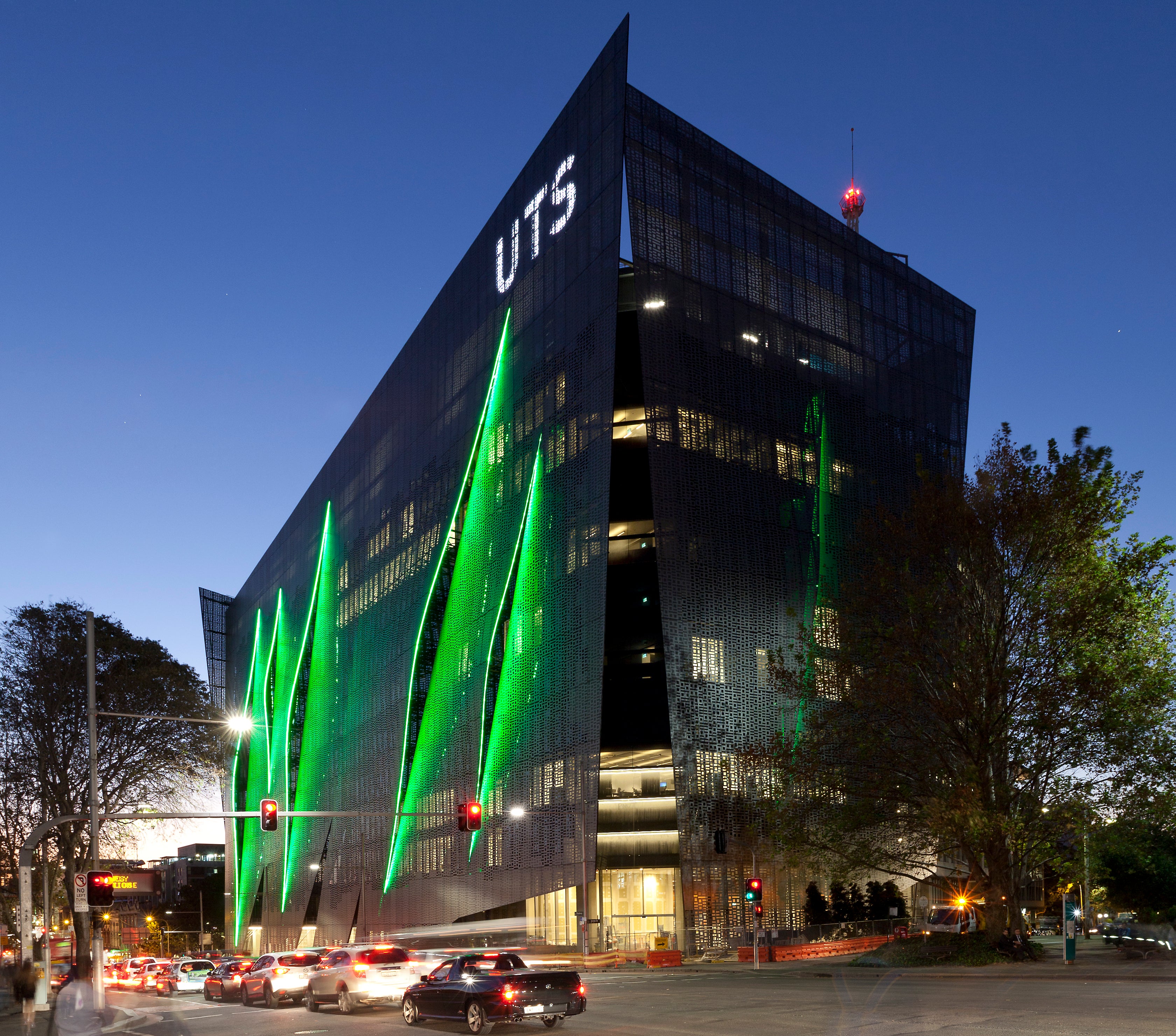UTS campus building at night featuring green light installations on the exterior and cars passing along the street.