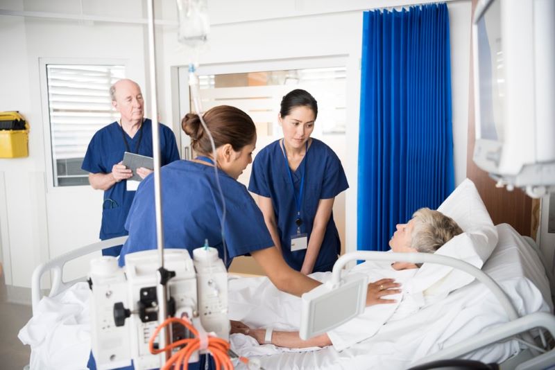 A nurse educator observing and guiding two nurses on patient care.