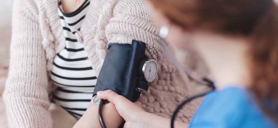 A female nurse testing the blood pressure of a female patient.