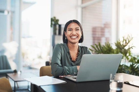 A UTS Online student smiling and studying on a laptop.