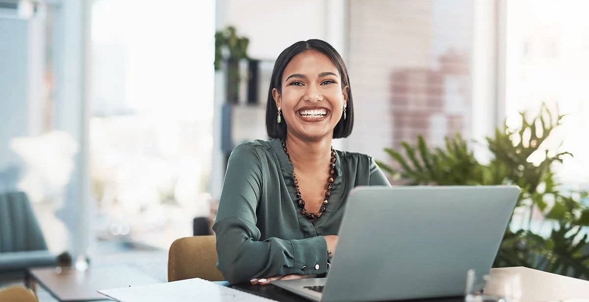 A UTS Online student smiling and studying on a laptop.