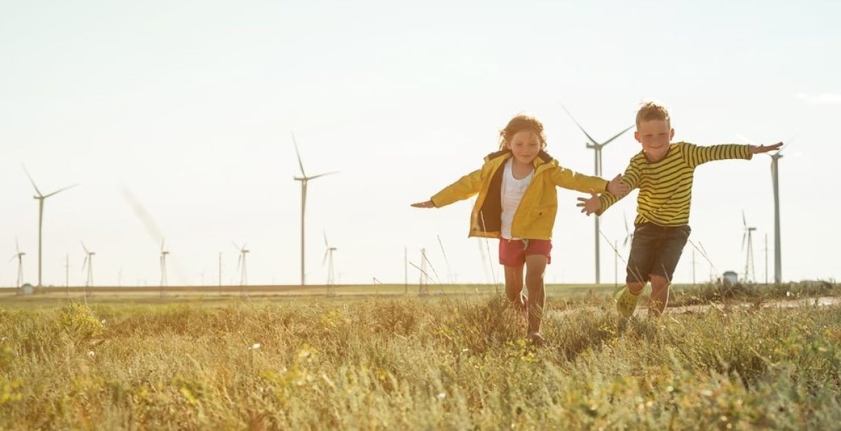 Children running in a field of wind turbines.