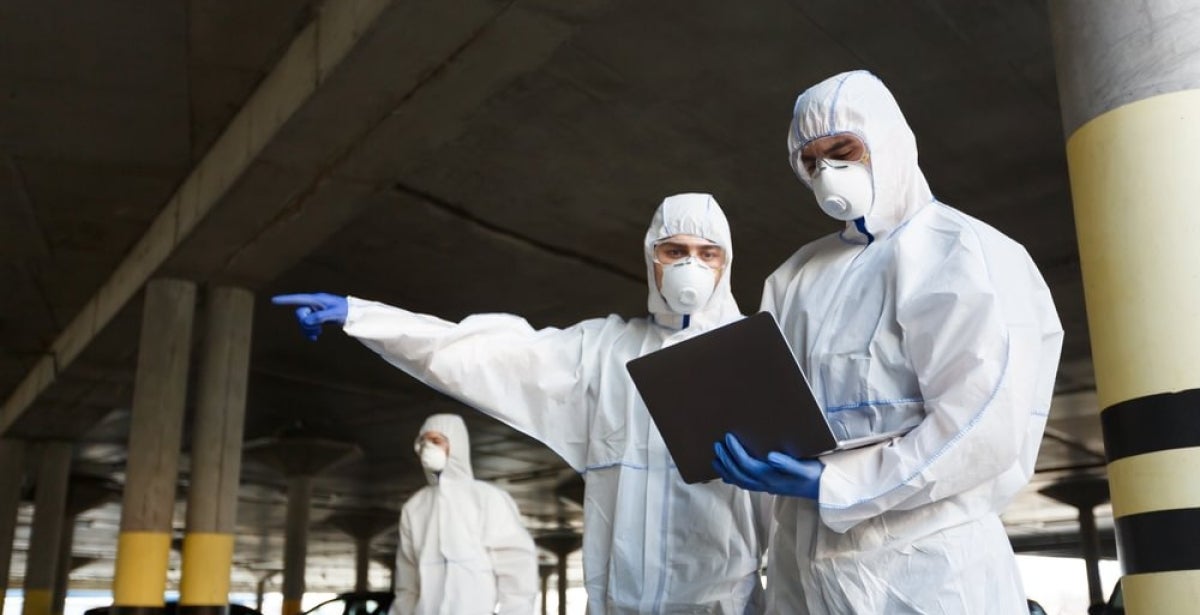 Public health researchers in protective clothing working outdoors.