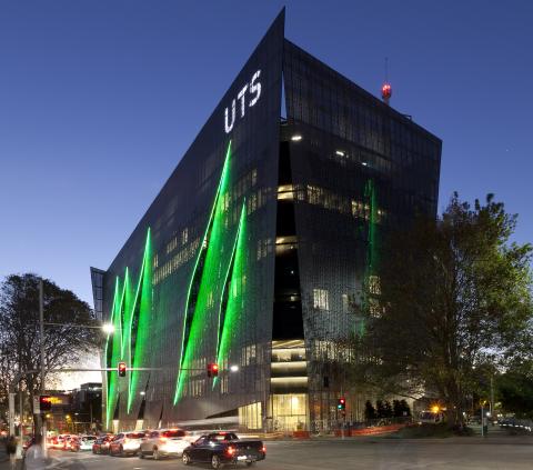 UTS campus building at night featuring green light installations on the exterior and cars passing along the street.