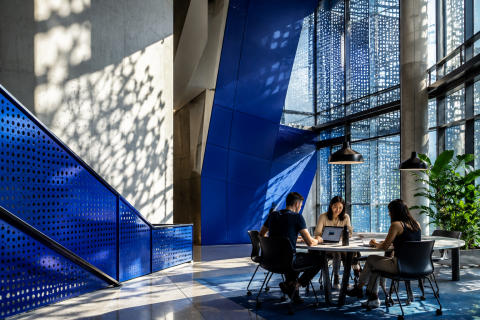 A modern, sun-drenched collaborative study space with striking geometric architectural details with a diverse group of young digital marketers.