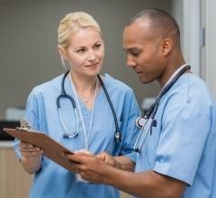 A nurse manager providing guidance to a nurse while they review information on a clipboard.