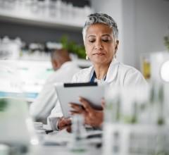 A health data analyst in a lab is using a tablet to review and analyse health information.