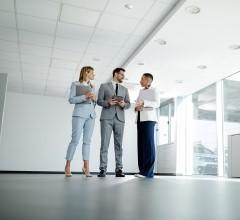 Three property valuers standing in an empty building, discussing property valuation.