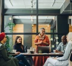 A diverse group of professionals engaged in discussion around a table in an office