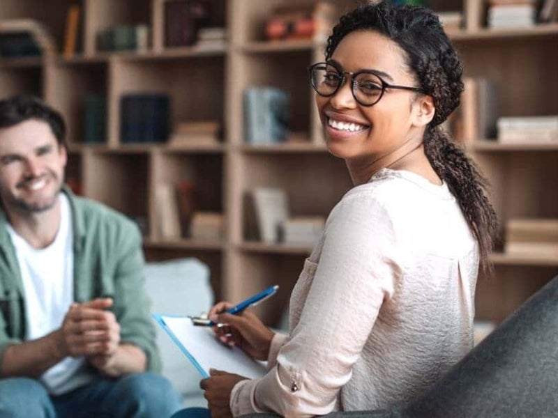 A psychologist and their patient smiling together.