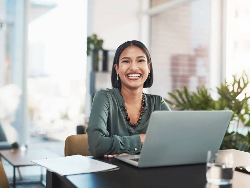 A UTS Online student smiling and studying on a laptop.