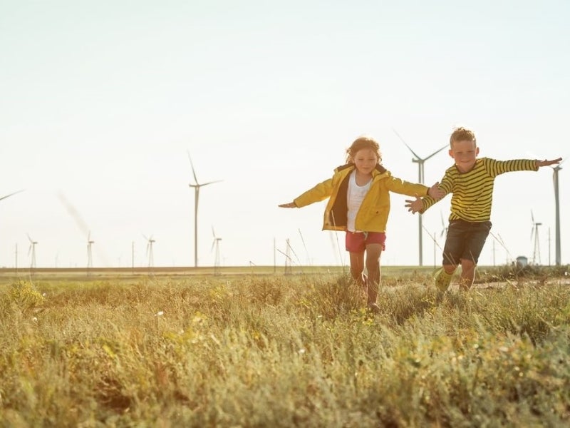 Children running in a field of wind turbines.