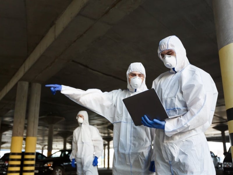 Public health researchers in protective clothing working outdoors.