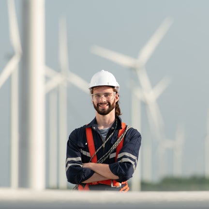 A man wearing a hard hat, with windmills in the background