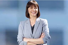 A confident woman in a business suit stands with her arms crossed, exuding professionalism and determination.