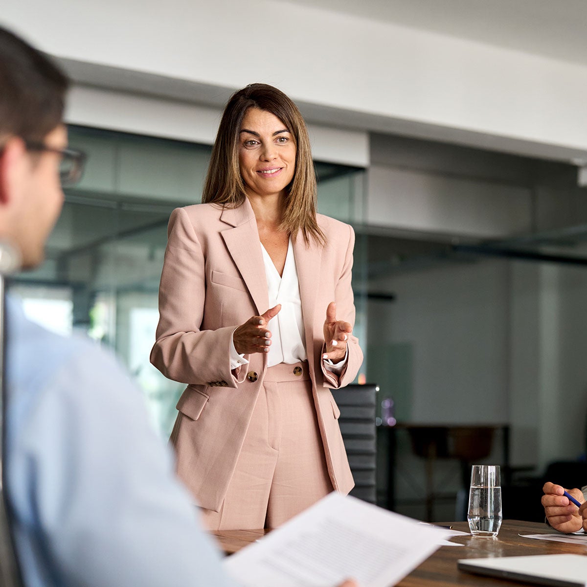 1. A woman in a business suit engages in conversation with a man, both appearing focused and professional.