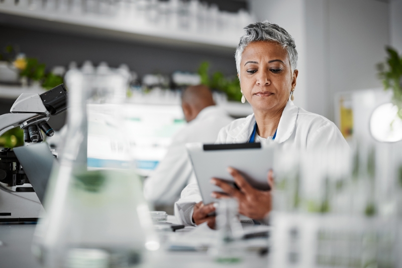 A health data analyst in a lab is using a tablet to review and analyse health information.