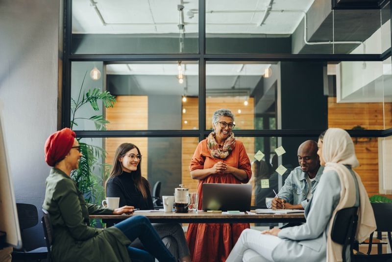 A diverse group of professionals engaged in discussion around a table in an office.