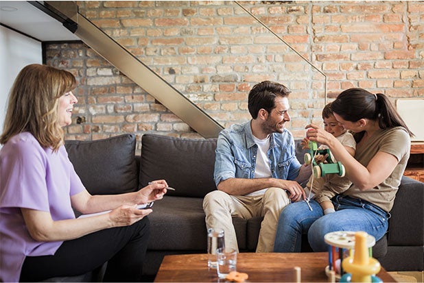 1. A family of four, including two adults and a child, sitting together on a couch, smiling and enjoying each other's company.