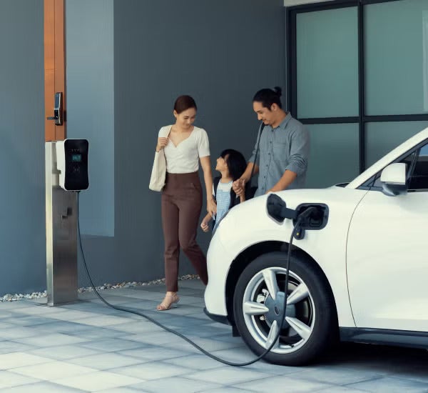 A family walking out of a building; a white car in the foreground.