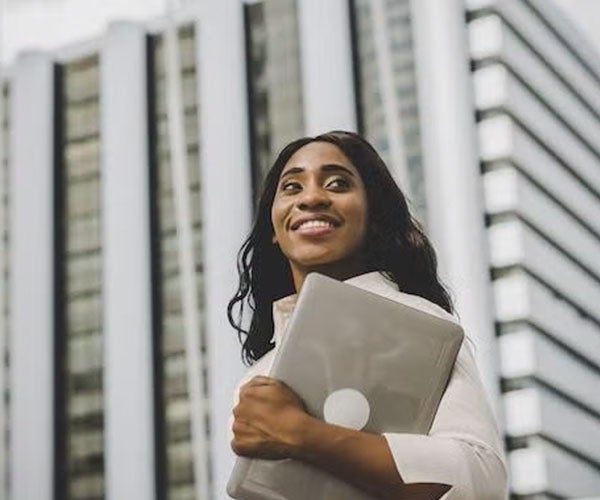 A student holding a tablet outdoors while discussing with a colleague.