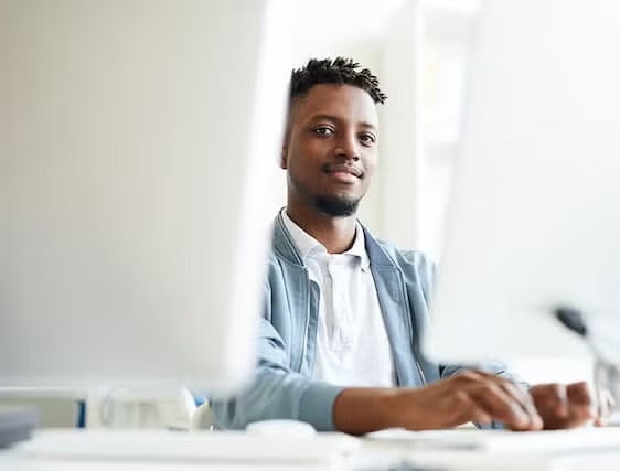 A young man working on a computer in a bright and modern office space.
